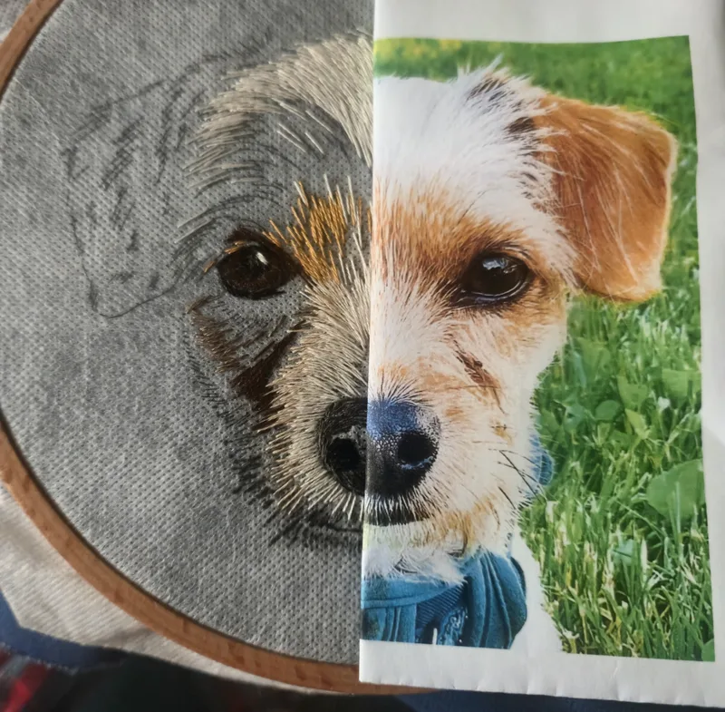 A half-finished hand-embroidered dog portrait held beside its reference photo