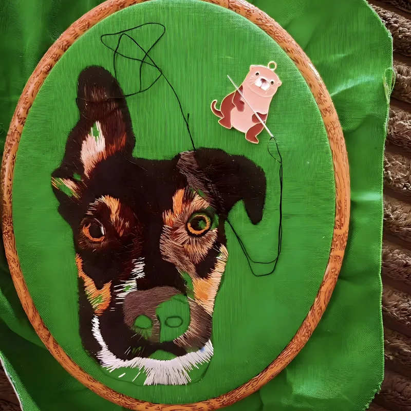 Custom dog portrait embroidery in progress, rich green tones on dark fabric