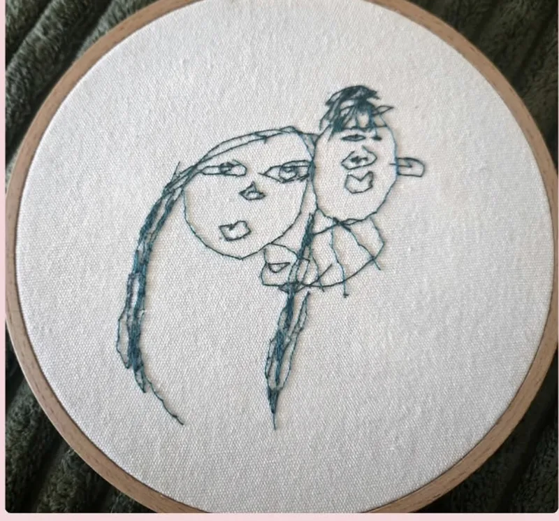 A child's drawing of two faces hand-embroidered onto a hoop